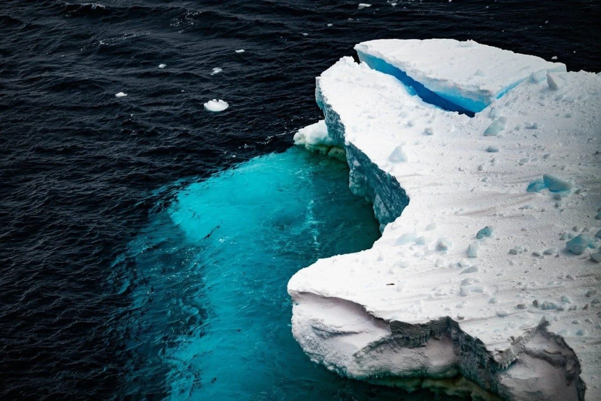 Bloque de hielo flotando en el océano Ártico con tonos azulados que reflejan el derretimiento polar