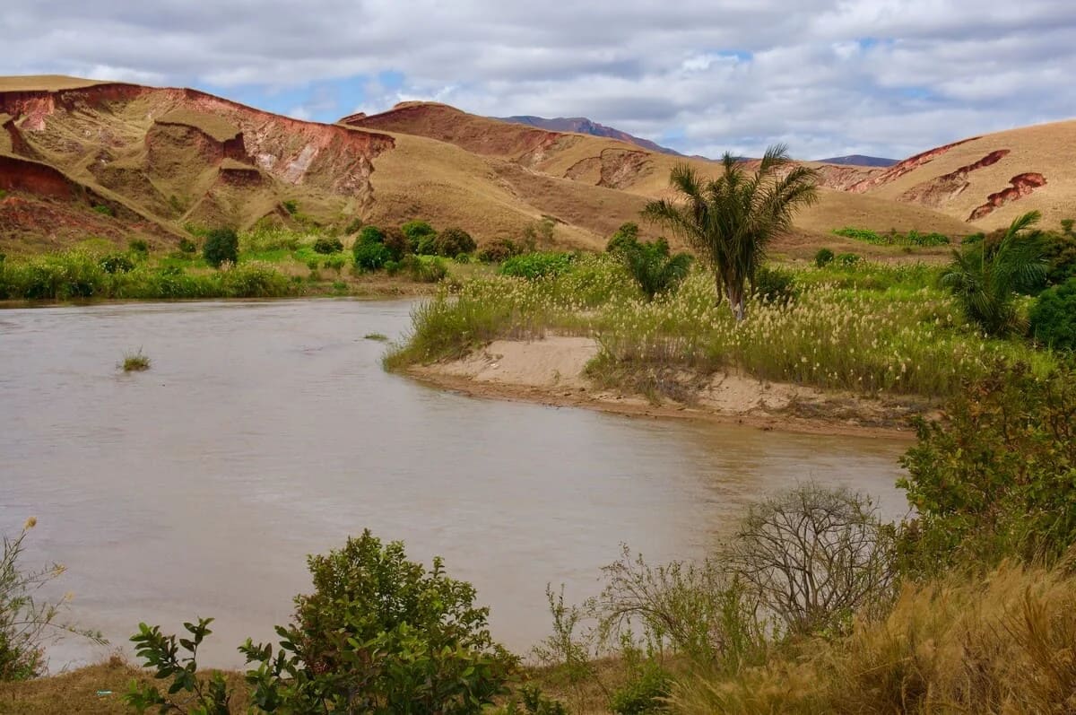 Paisaje de la meseta central de Madagascar con colinas erosionadas y vegetación dispersa bajo un cielo nublado