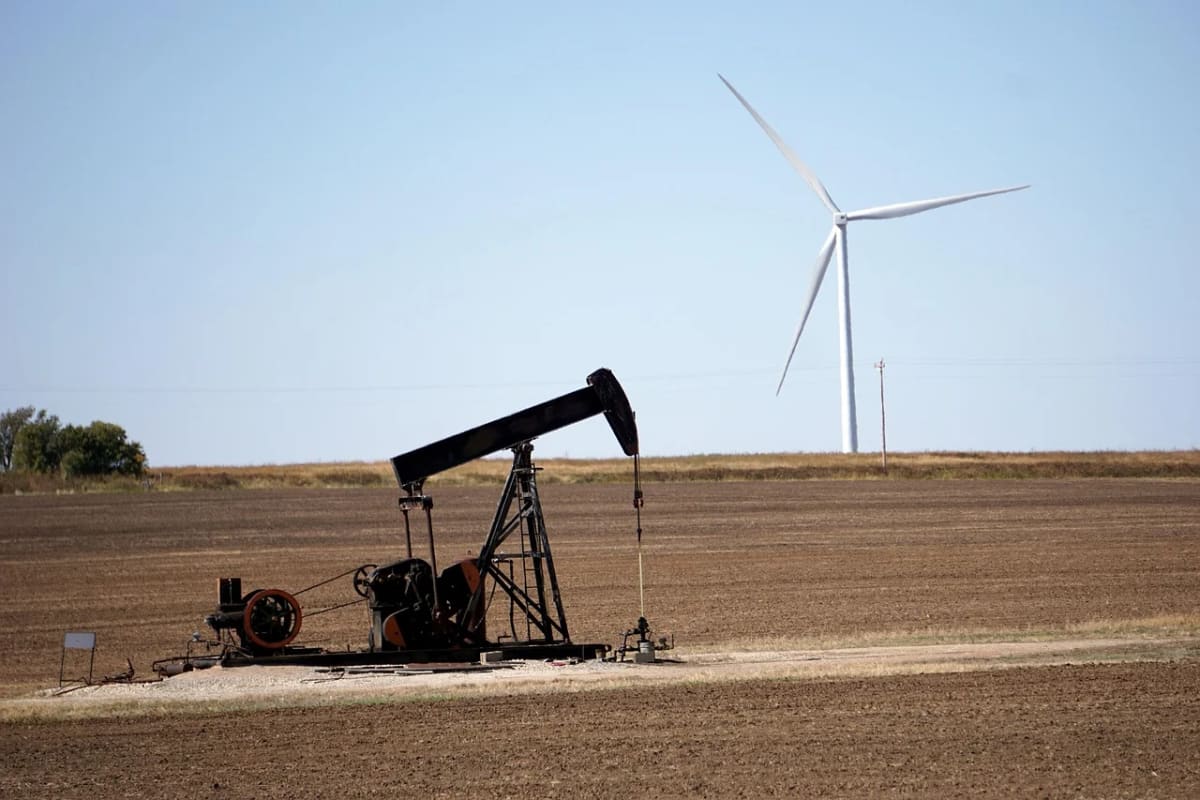 Bomba extractora de petróleo y aerogenerador en un campo abierto