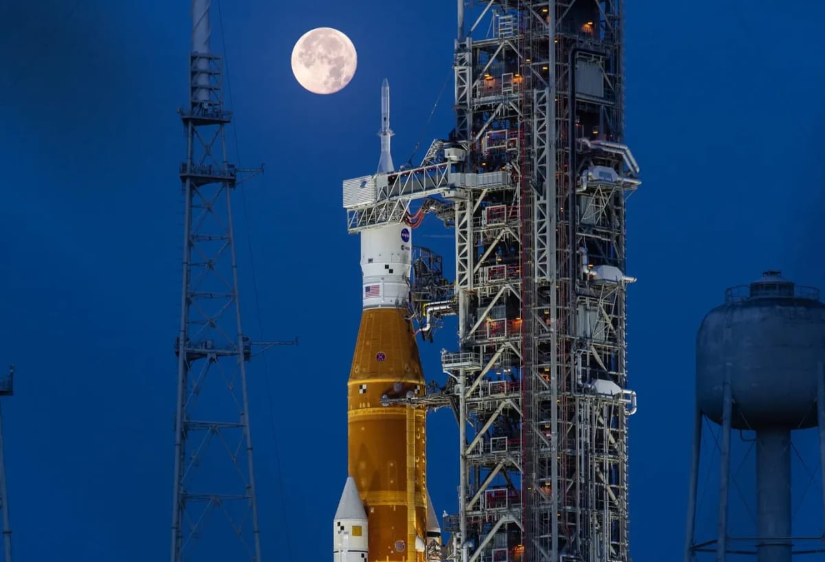 El cohete SLS y la nave Orion de la misión Artemis I en la plataforma de lanzamiento del Centro Espacial Kennedy, con la luna llena iluminando el fondo nocturno