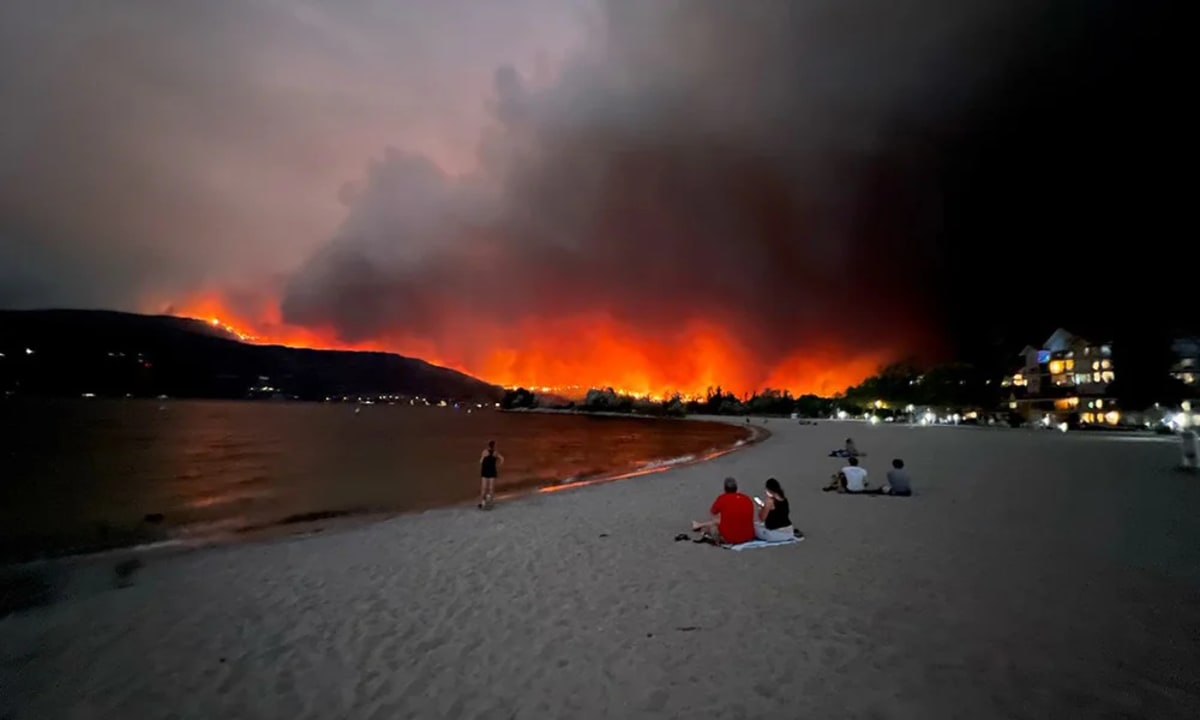 Incendio forestal activo cerca del lago Okanagan con columnas de humo elevándose sobre el paisaje