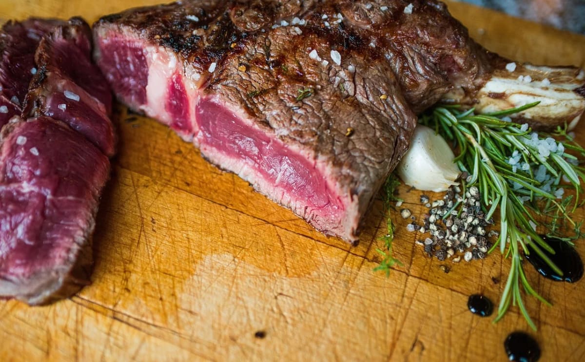Carne a la parrilla poco hecha sobre una tabla de madera