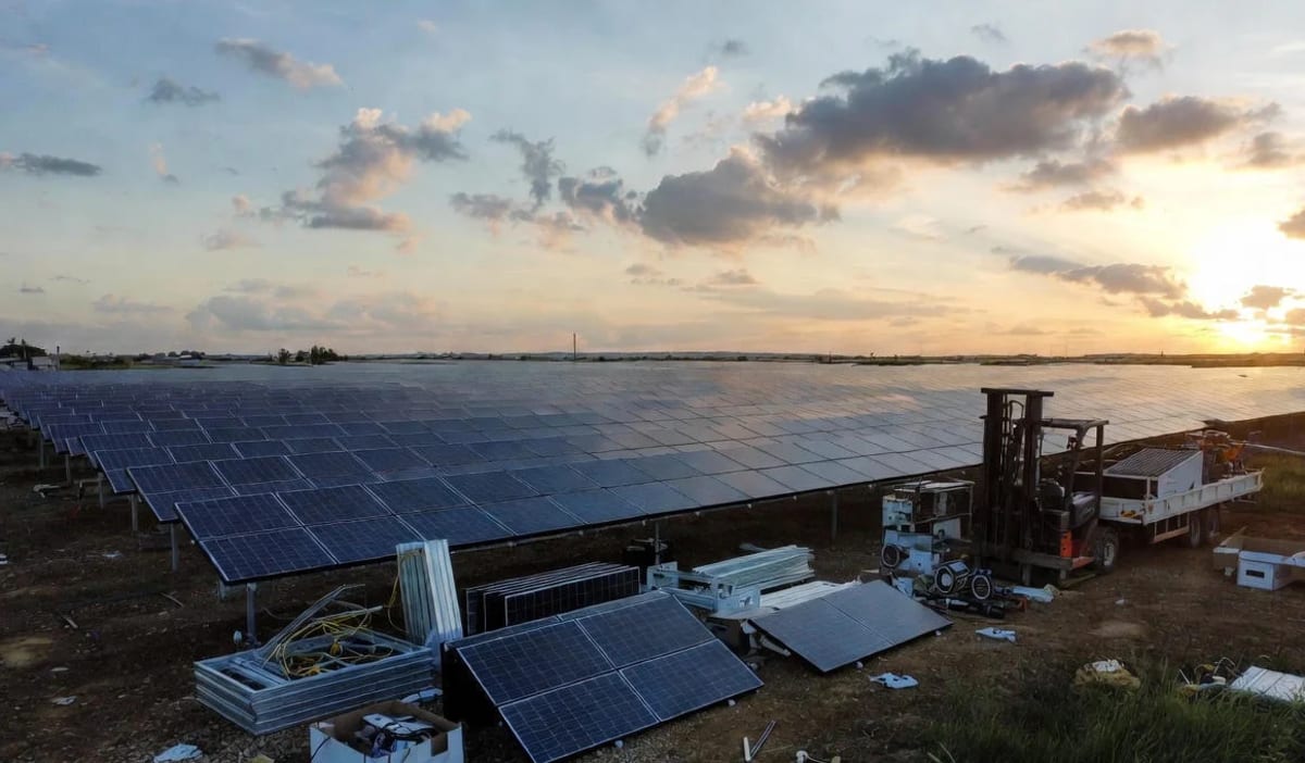 Campo solar con paneles a medio instalar al atardecer