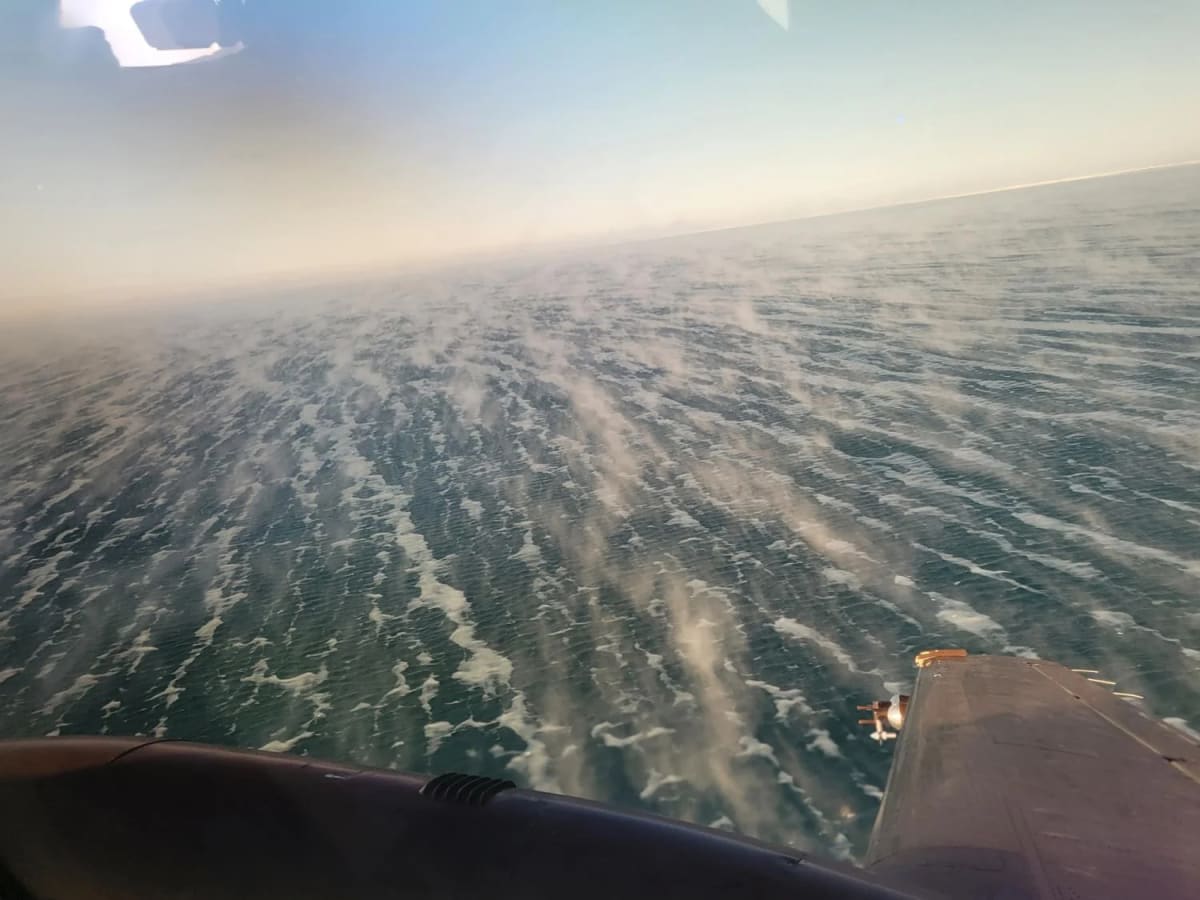 Vista aérea desde un avión mostrando humo marino formándose sobre aguas abiertas del Ártico