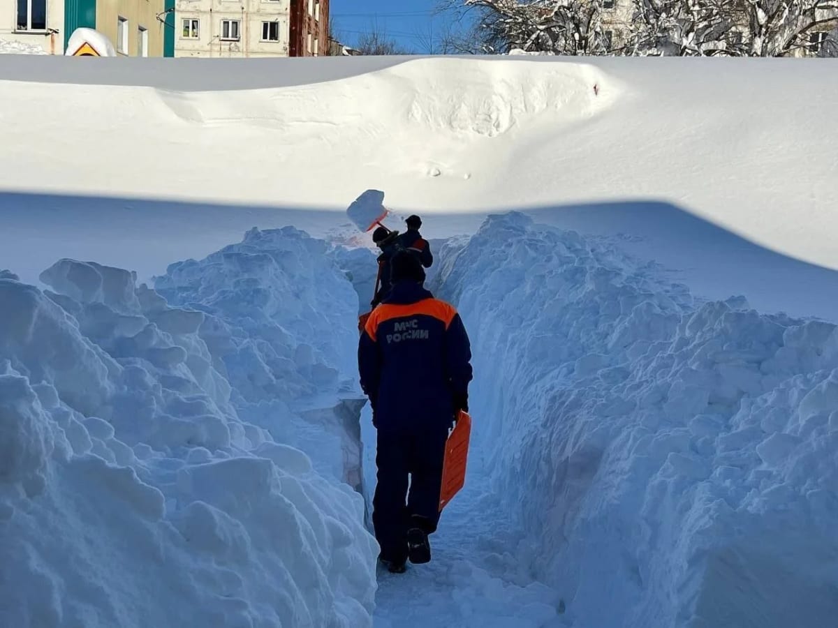 Persona caminando por un pasillo abierto entre muros de nieve acumulada en una ciudad de Kamchatka