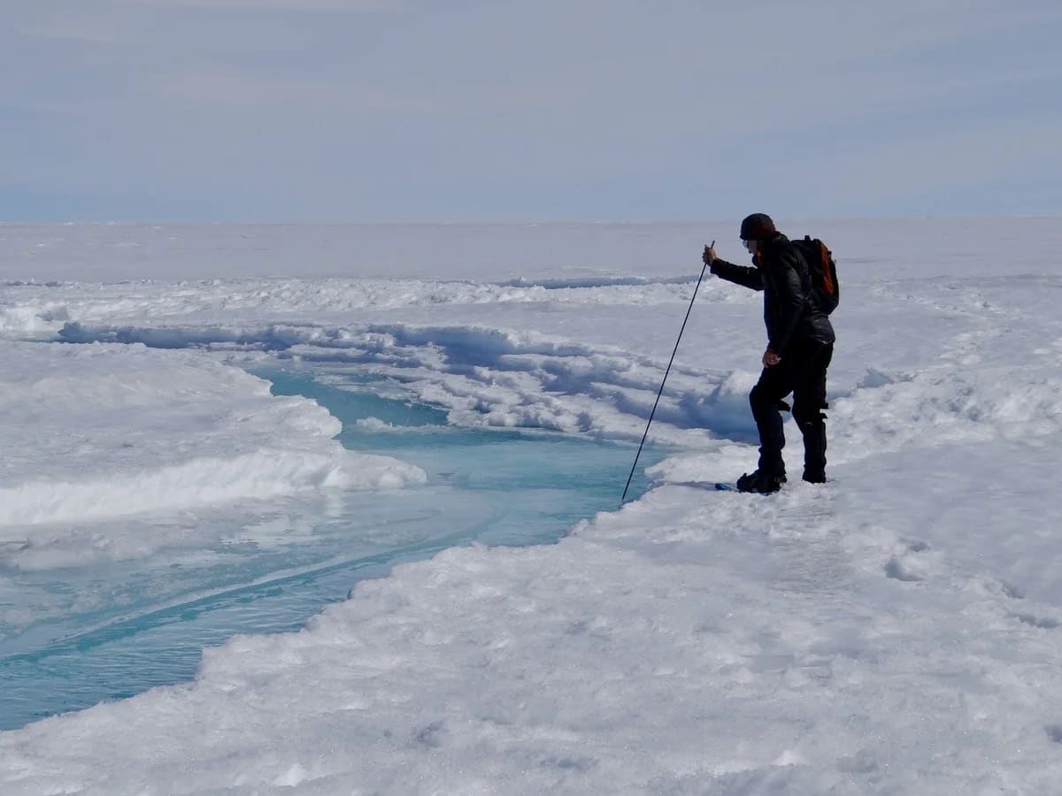 Investigador caminando sobre el hielo junto a un arroyo de deshielo