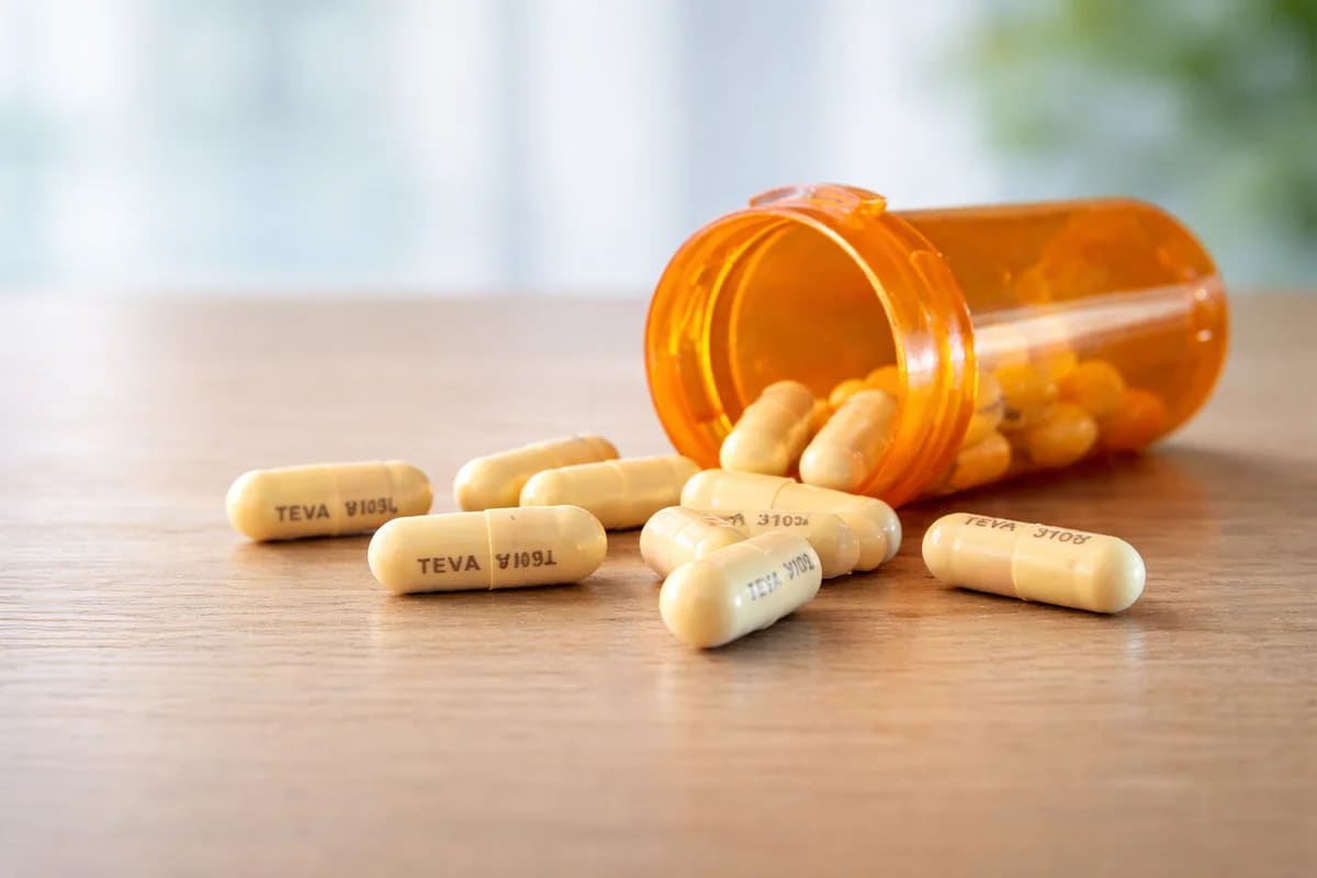 Frasco ámbar con cápsulas antibióticas sobre mesa clara