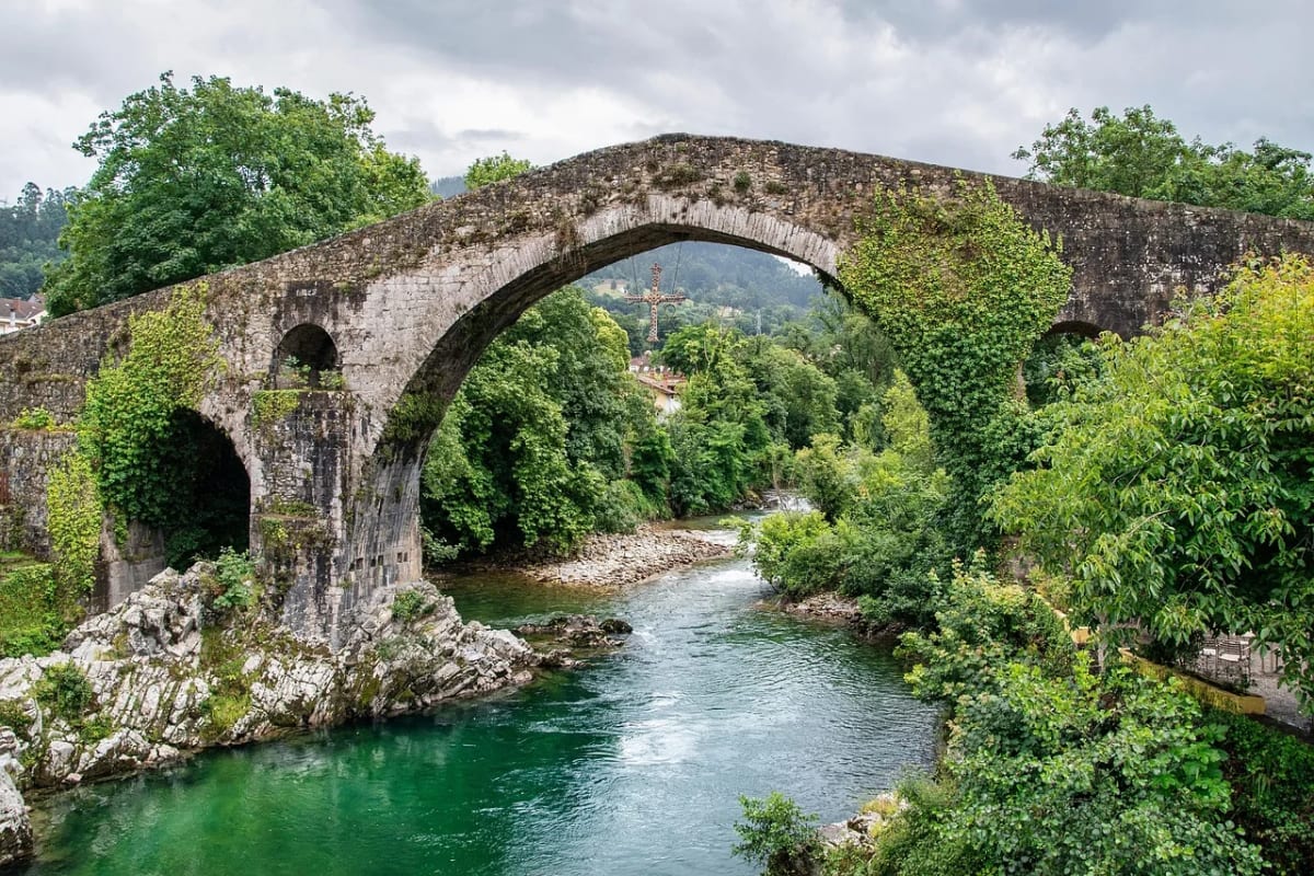 Puente medieval de piedra sobre un río verde