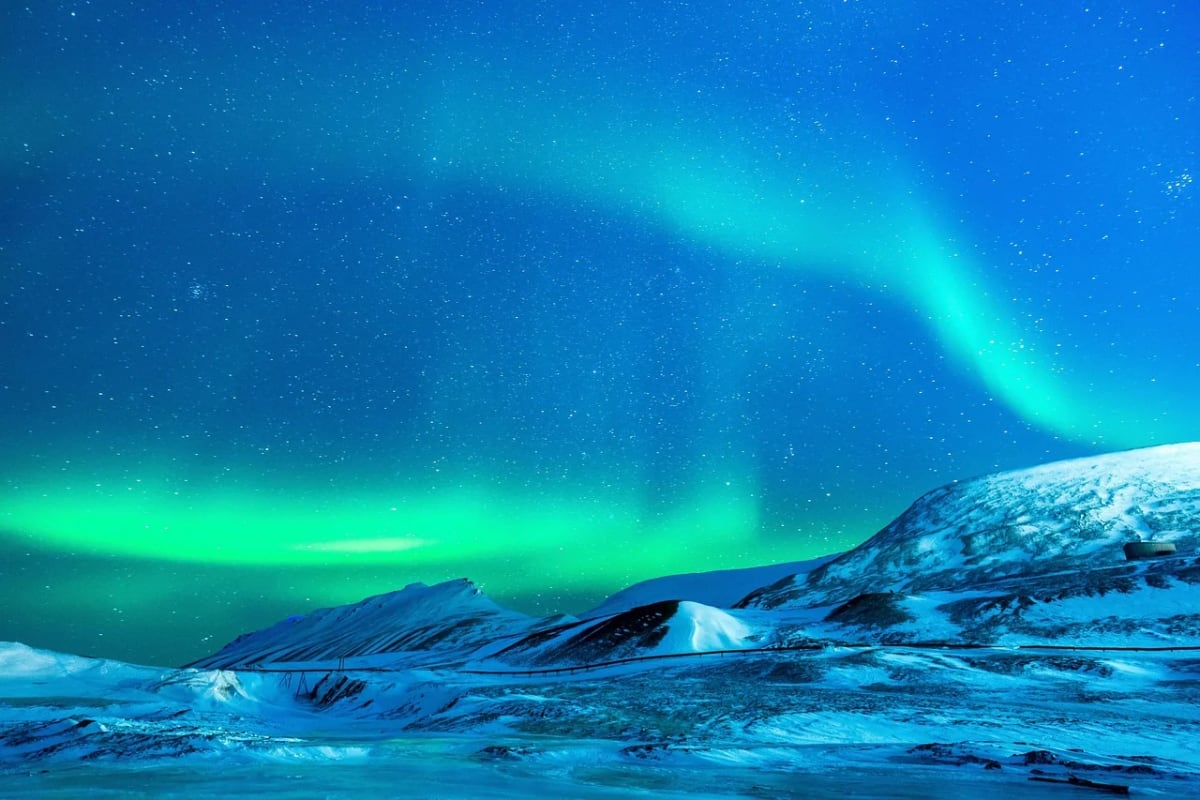 Aurora austral iluminando un paisaje nevado bajo el cielo nocturno