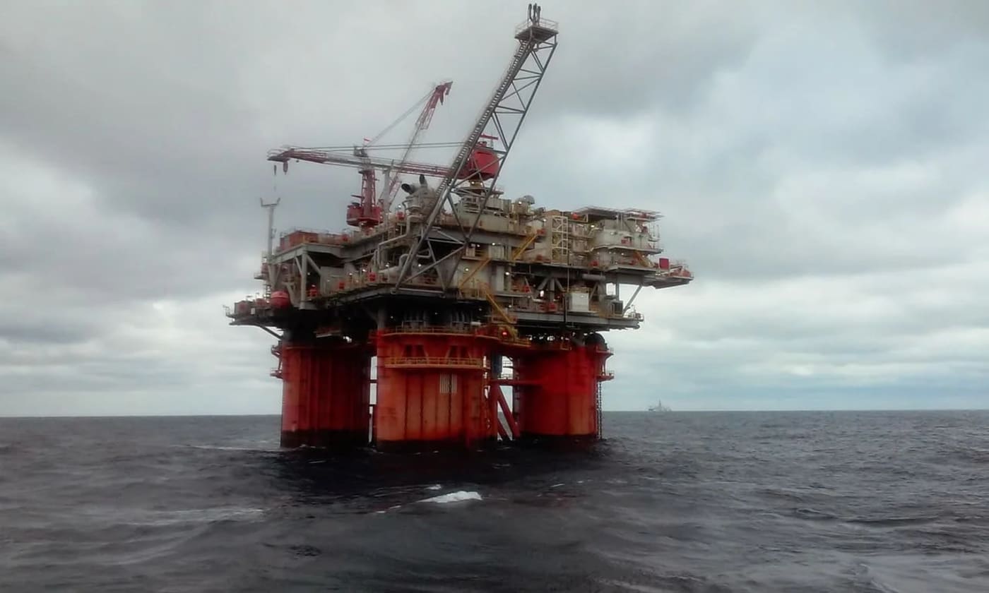 Plataforma petrolera en alta mar, destacando estructuras metálicas sobre un océano bajo un cielo nublado.