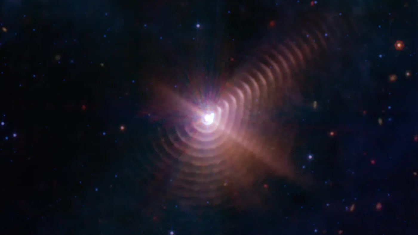 Imagen infrarroja del sistema binario Wolf-Rayet 140, capturada por el telescopio espacial James Webb, mostrando anillos de polvo concéntricos formados por la interacción de dos estrellas masivas.