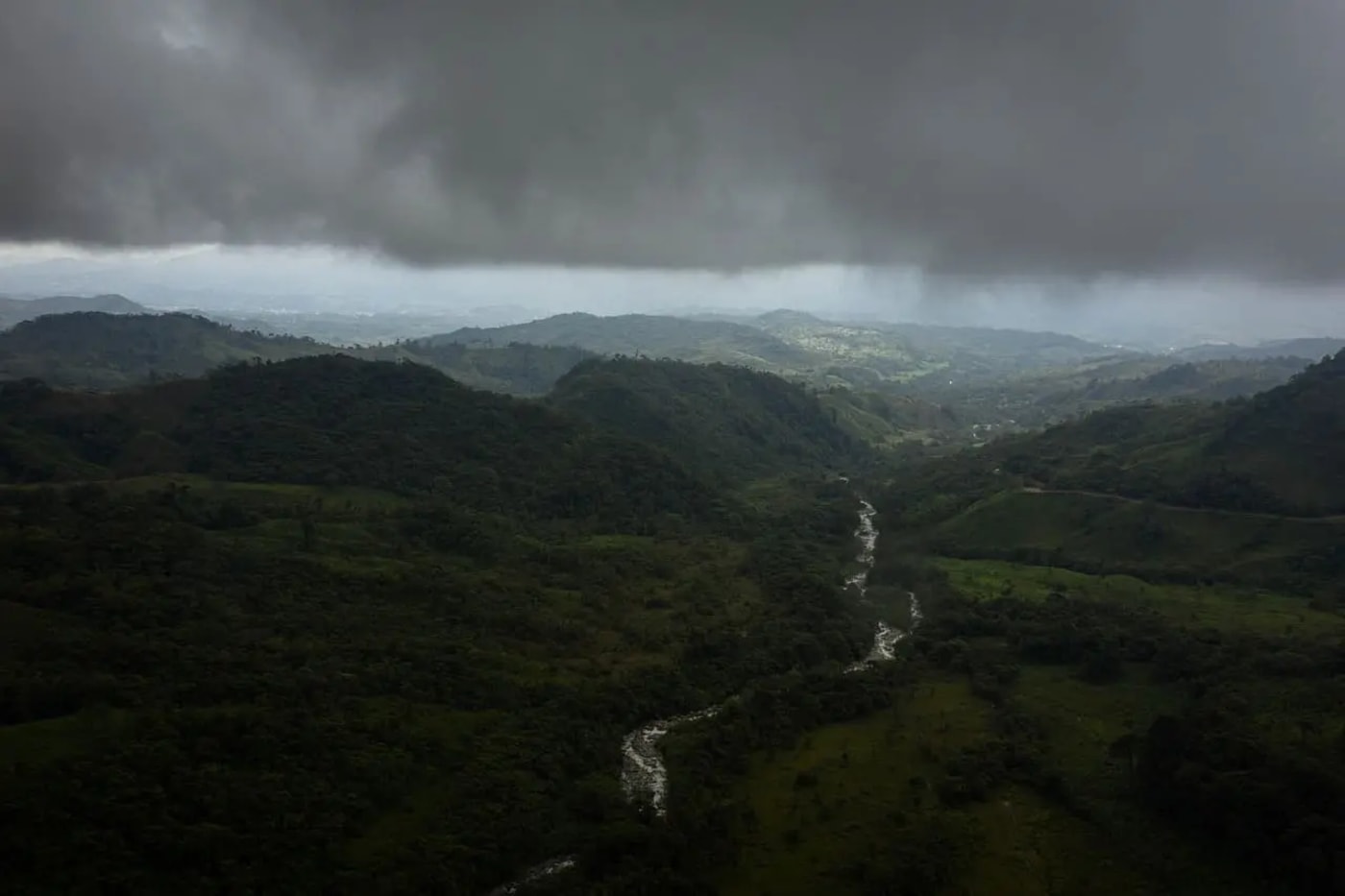 Vista aérea de la Amazonía con densas montañas cubiertas de selva y un cielo oscuro con nubes de tormenta.