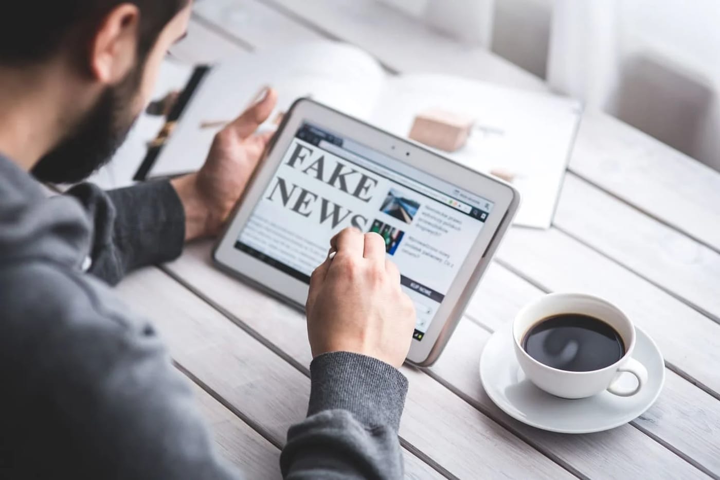 Persona leyendo noticias falsas en una tablet como símbolo de la sobreinformación