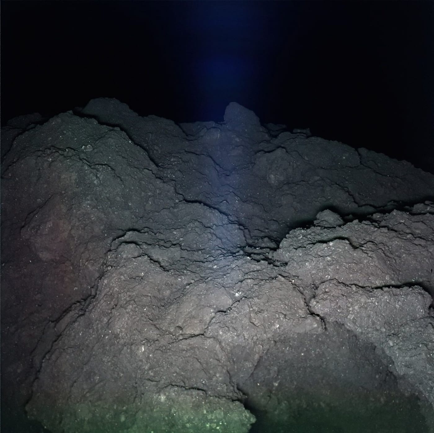Superficie rocosa del asteroide Ryugu captada en alta resolución por una misión conjunta de NASA y JAXA, rodeada de oscuridad absoluta en el espacio