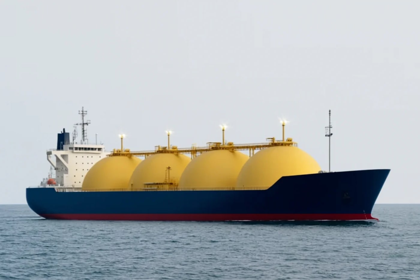 Barco de GNL navegando en mar abierto, con grandes esferas amarillas de almacenamiento y casco azul oscuro con franja roja, sobre un fondo sin montañas