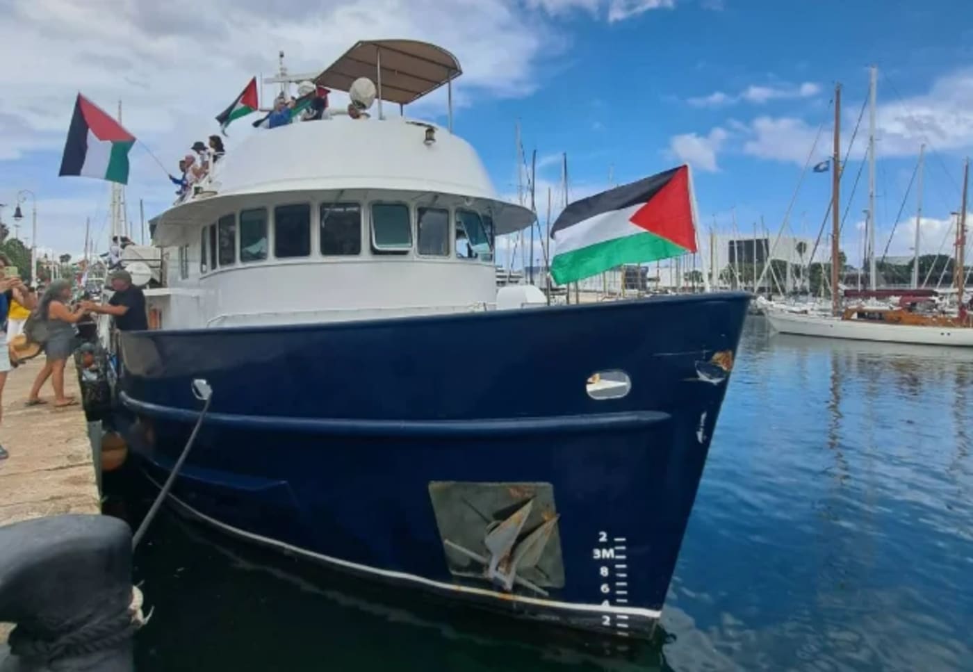 Barco de la flotilla Global Sumud en puerto, con banderas palestinas ondeando antes de zarpar hacia Gaza