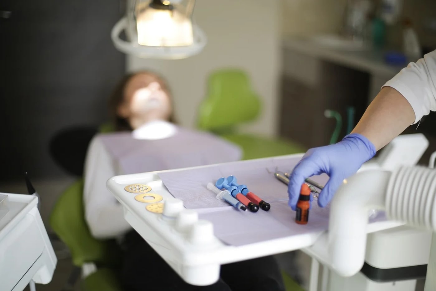 Dentista prepara instrumental médico mientras un paciente espera en el sillón