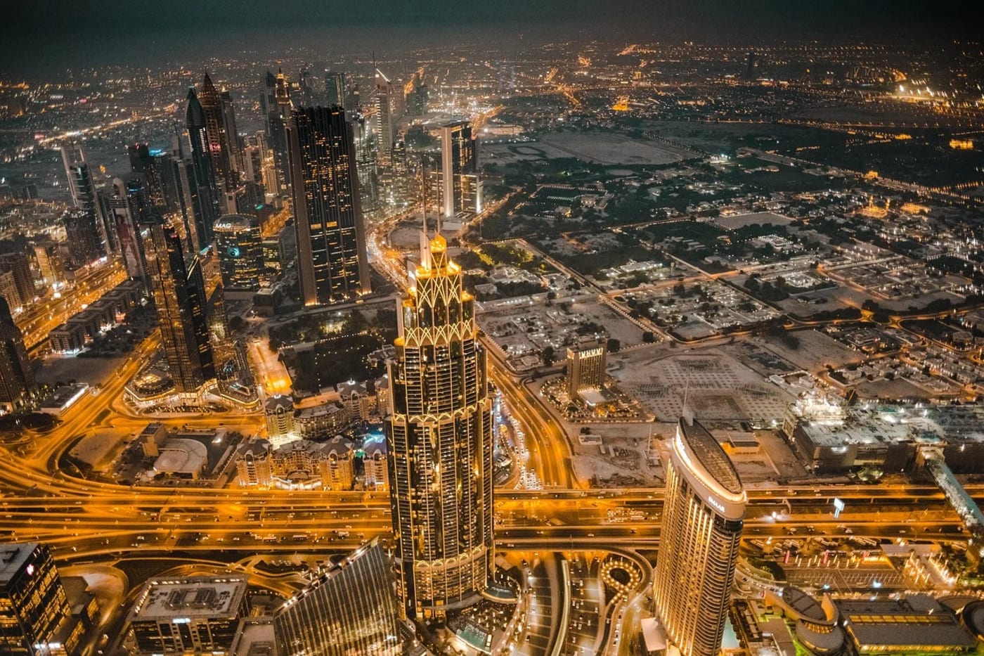 Vista aérea nocturna del centro de Dubái con rascacielos iluminados y autopistas