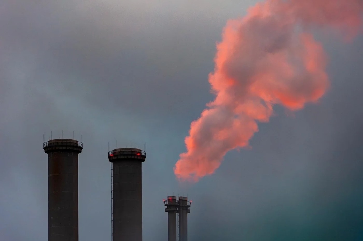Chimeneas industriales emitiendo humo rosado al amanecer