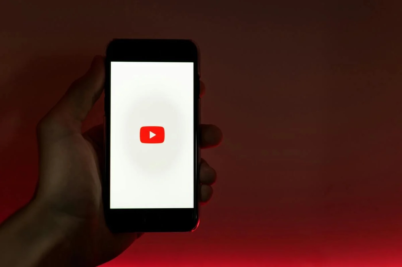 Persona sosteniendo un teléfono móvil que muestra el logotipo de YouTube en la pantalla