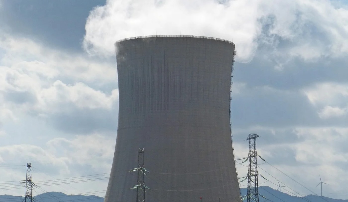 Torre de refrigeración de una central eléctrica emitiendo vapor bajo un cielo nublado
