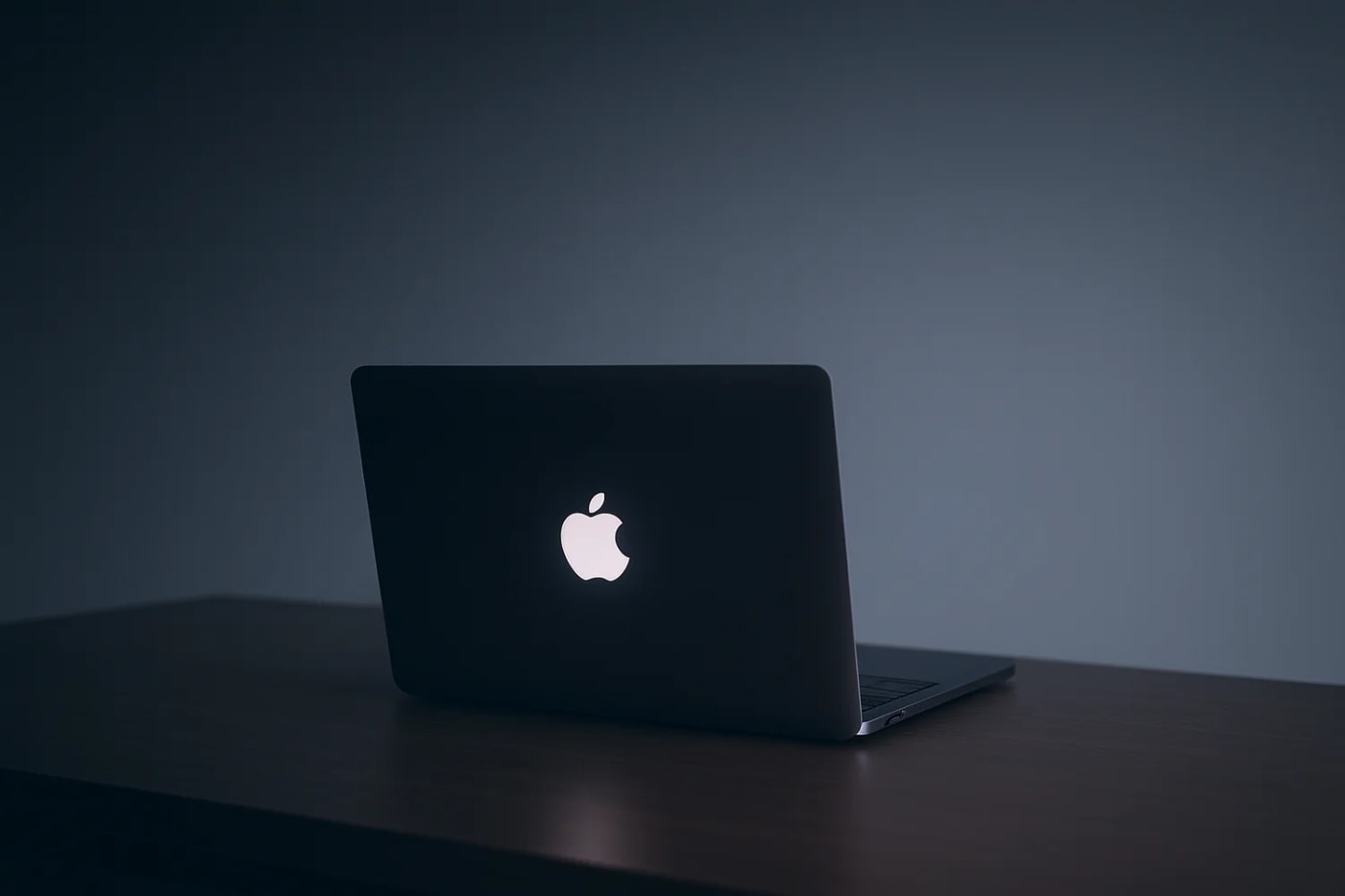 MacBook con el logo iluminado sobre una mesa
