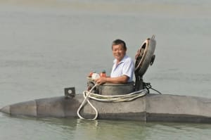 Hombre probando un submarino casero eléctrico en un río