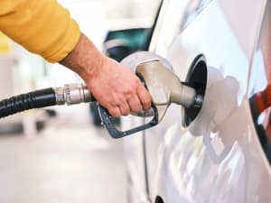 Persona repostando combustible en un vehículo en una gasolinera
