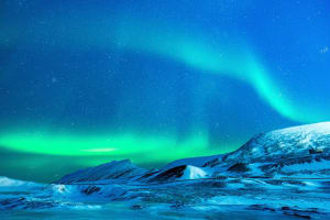Aurora austral iluminando un paisaje nevado bajo el cielo nocturno