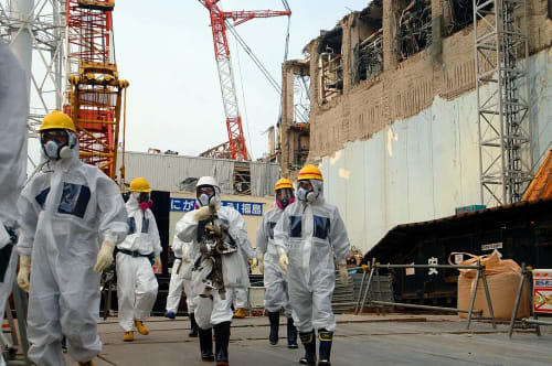 Técnicos del OIEA con equipos de protección observando instalaciones en la Unidad 4 de la central nuclear de Fukushima Daiichi en 2013