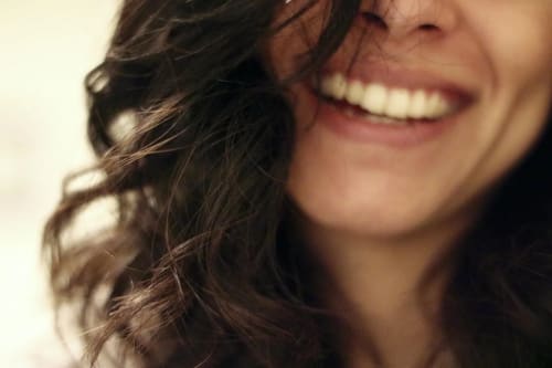 Rostro parcial de una mujer con cabello suelto y una amplia sonrisa
