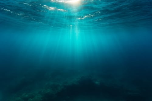 Vista submarina realista con rayos de luz atravesando la superficie del océano en aguas claras y profundas