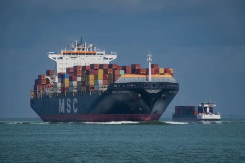 Buque portacontenedores navegando en mar abierto con carga apilada.