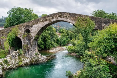 Puente medieval de piedra sobre un río verde