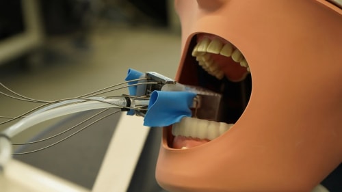 Robot dental en miniatura trabajando sobre un modelo de dientes