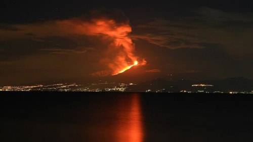 Erupción del volcán Etna iluminando el cielo nocturno vista desde Calabria