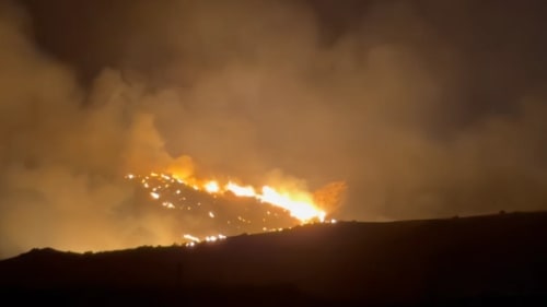 Incendio forestal avanzando por una zona montañosa durante la noche
