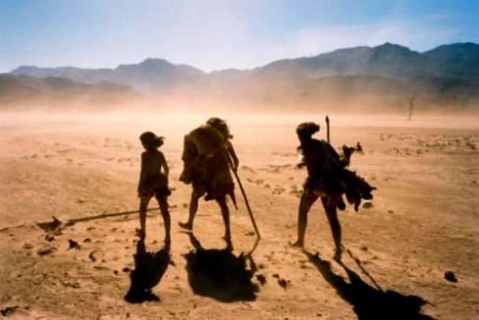 Humanos prehistóricos caminando a través de un paisaje desértico