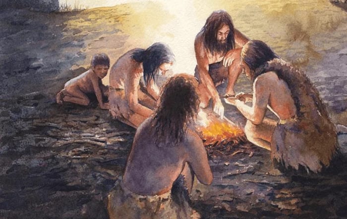 Representación artística de un grupo de humanos prehistóricos reunidos alrededor de una fogata, destacando la importancia del fuego en la evolución y desarrollo social de la humanidad