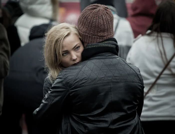 Mujer abrazando a un hombre en medio de una multitud