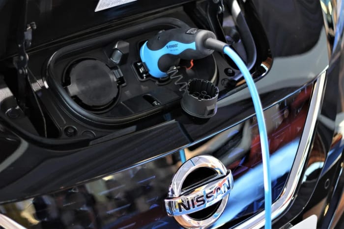 Un coche eléctrico Nissan conectado a su punto de carga durante el proceso de recarga