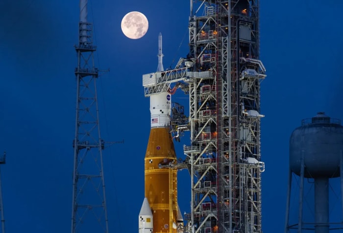 El cohete SLS y la nave Orion de la misión Artemis I en la plataforma de lanzamiento del Centro Espacial Kennedy, con la luna llena iluminando el fondo nocturno