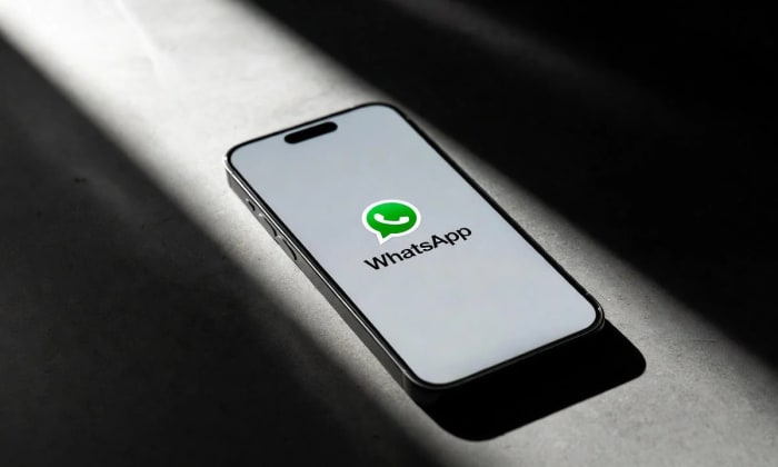 Un teléfono móvil encendido muestra el logo de WhatsApp sobre un fondo claro