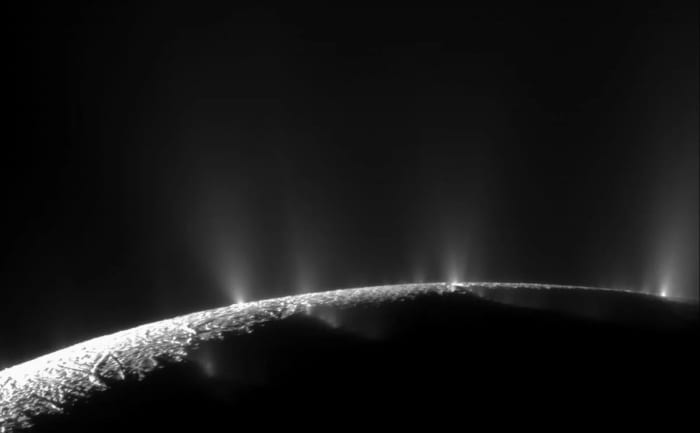 Plumas brillantes de hielo y vapor elevándose desde el polo sur de Encélado, captadas por la sonda Cassini