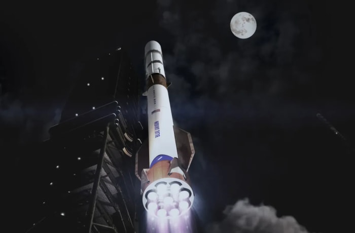 El cohete New Glenn iluminado mientras se eleva desde la plataforma de lanzamiento bajo un cielo nocturno con la Luna al fondo