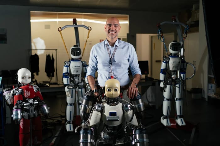 Daniele Pucci posando con robots humanoides del Instituto Italiano de Tecnología