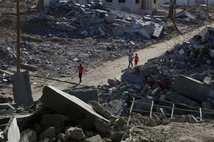 Personas caminando entre edificios destruidos en una zona devastada de Gaza