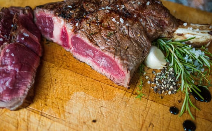 Carne a la parrilla poco hecha sobre una tabla de madera