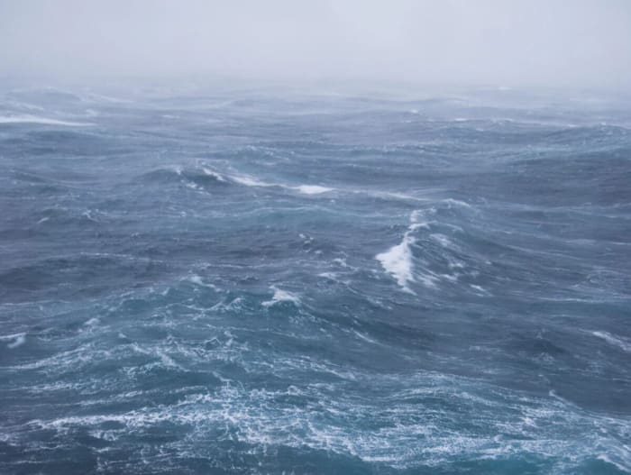 Mar agitado con olas altas y espuma blanca bajo un cielo gris y tormentoso