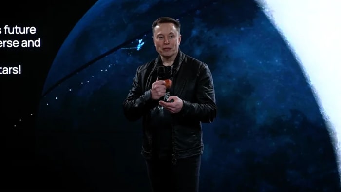 Elon Musk durante una presentación de xAI con una imagen del espacio proyectada al fondo